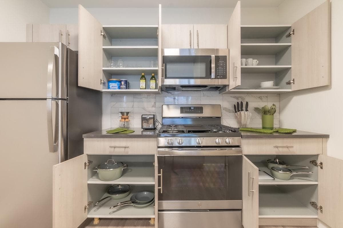 Fully stocked kitchen with modern stainless steel appliances. Pots, cutting boards and more neatly tucked away in the cabinets 